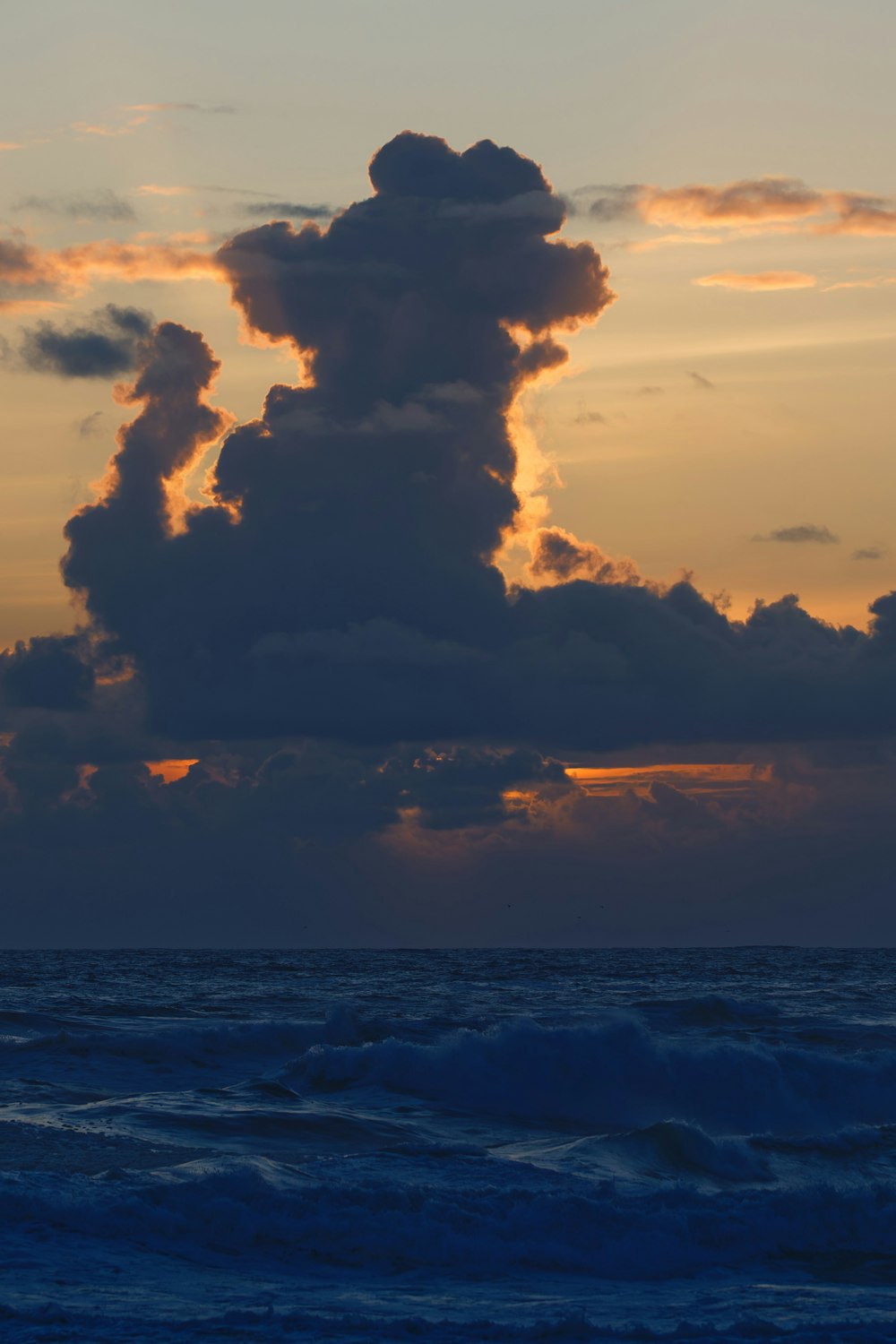 a large cloud in the sky over a body of water