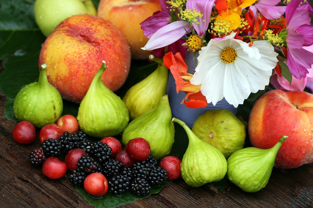 a wooden table topped with lots of fruit and flowers