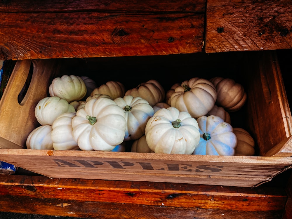 a wooden box filled with lots of white pumpkins