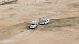 Hands raised in a moment of praise atop a hill overlooking a vast off-roading landscape.