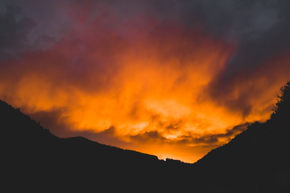 a sunset view of a mountain range with clouds in the sky