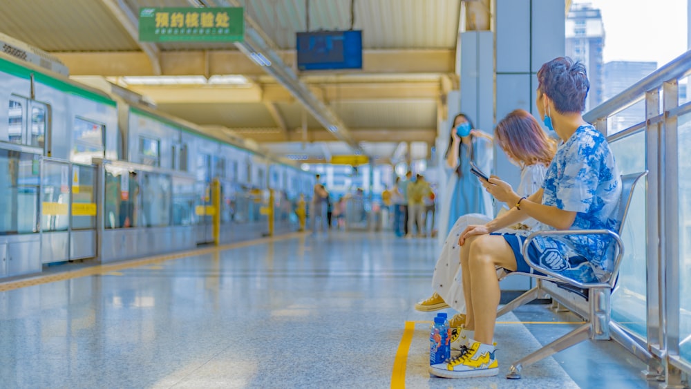 a man and a woman sitting on a bench in a train station