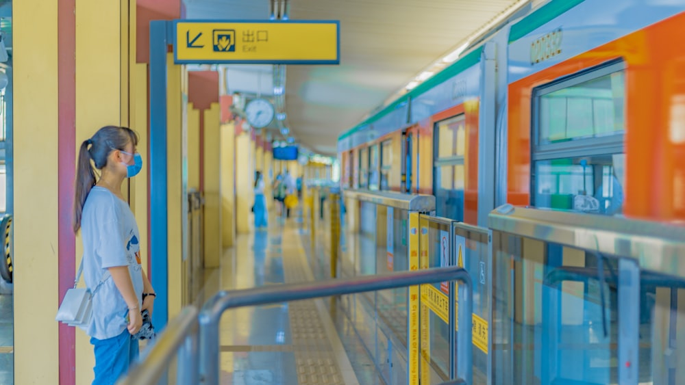 a woman wearing a face mask standing in front of a train