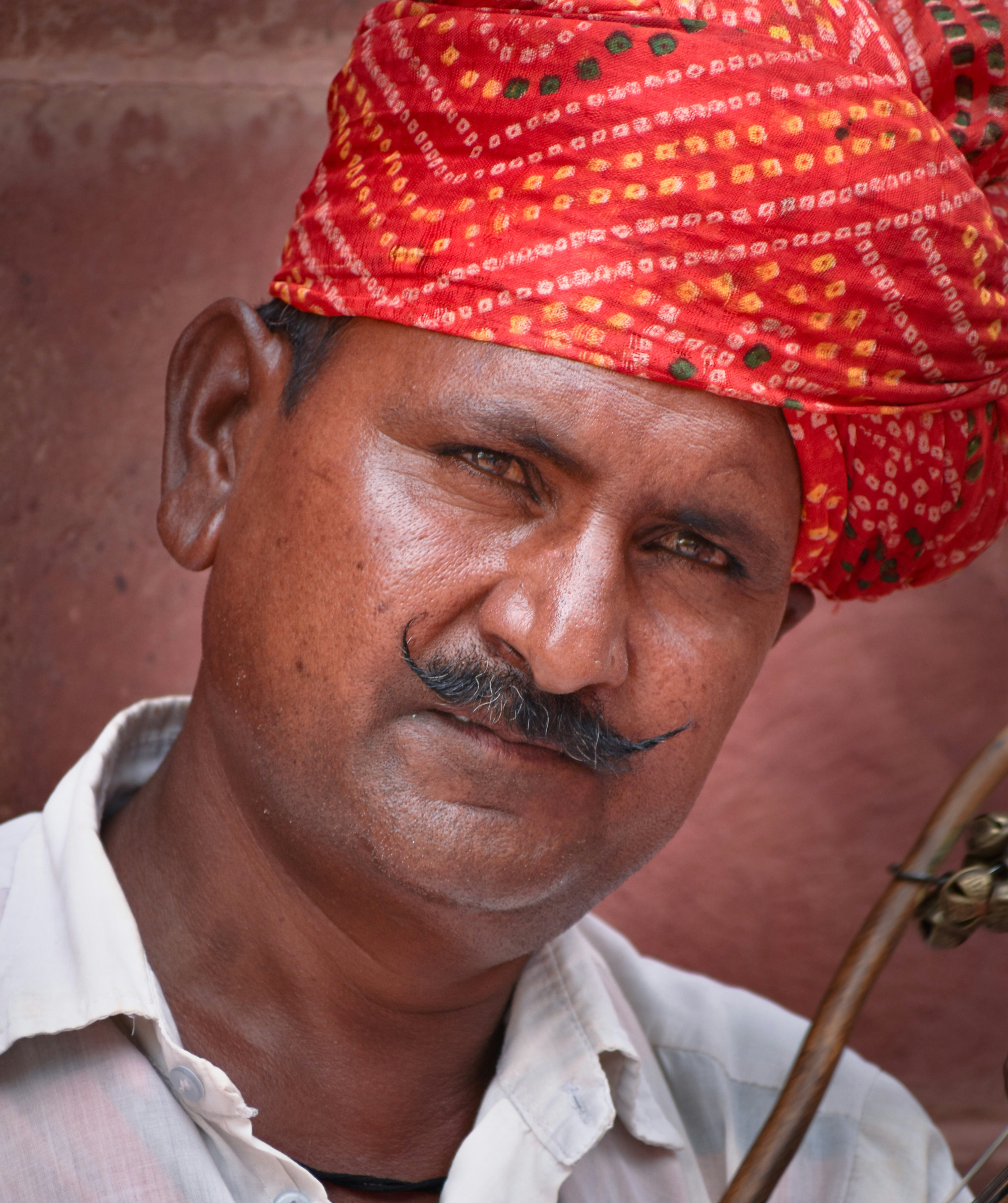 a man wearing a red turban with a pipe in his hand