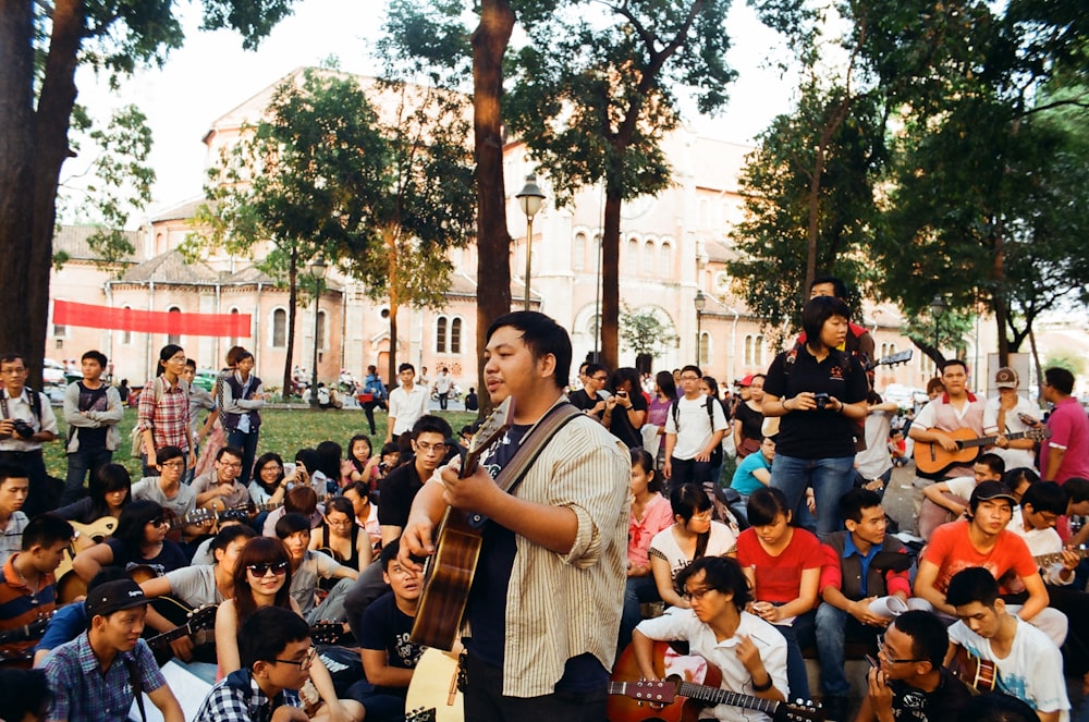 Un uomo che suona una chitarra di fronte a una folla di persone