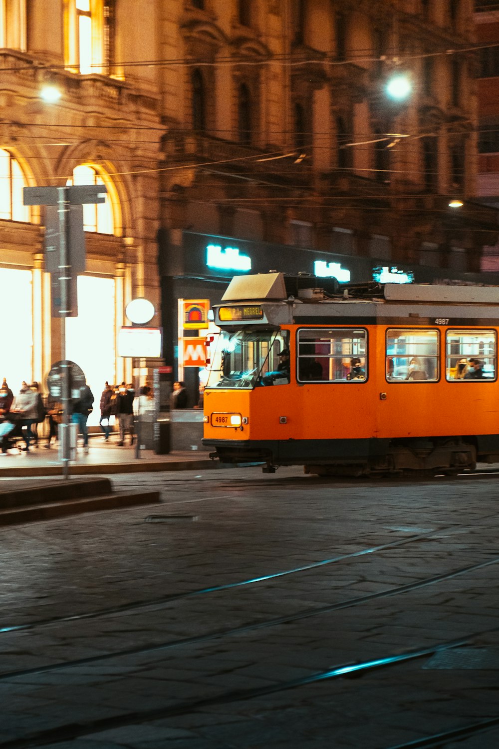 an orange trolley car on a city street at night