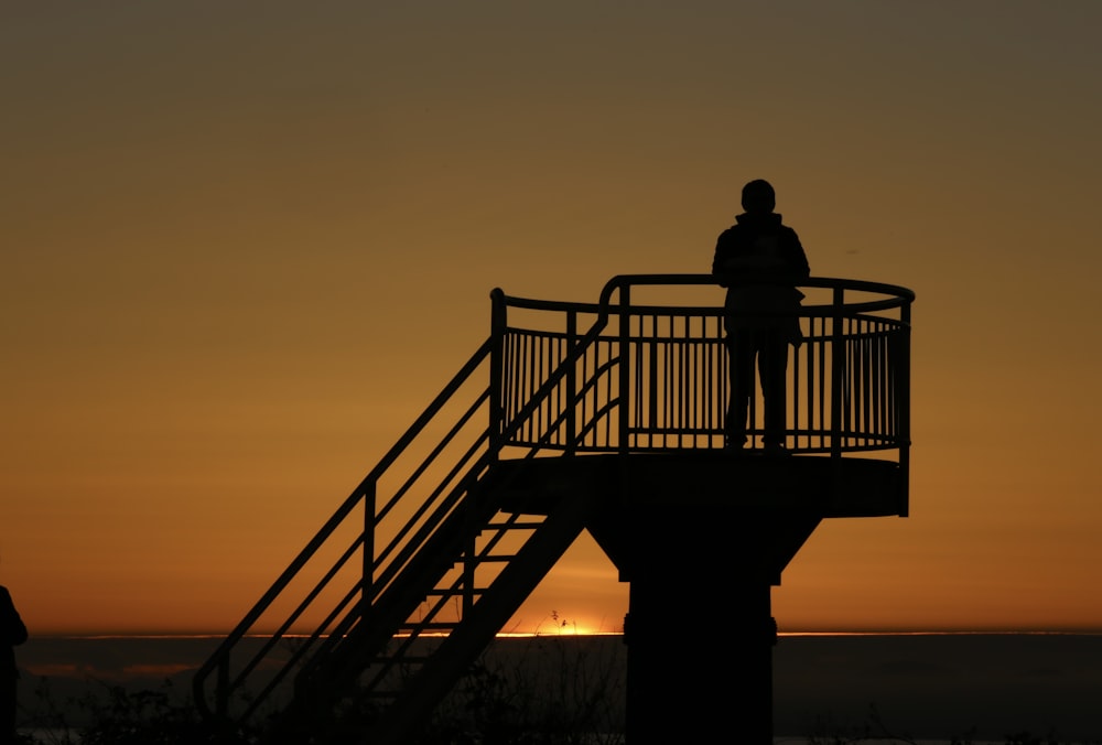 a person standing on a balcony at sunset