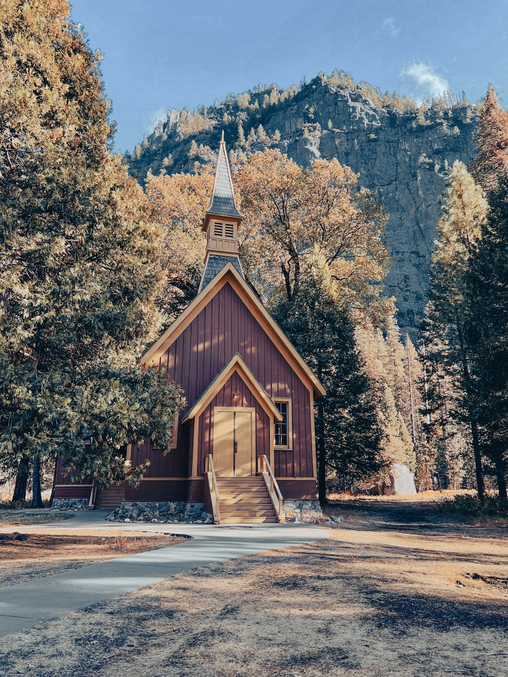 a wooden church with a steeple surrounded by trees