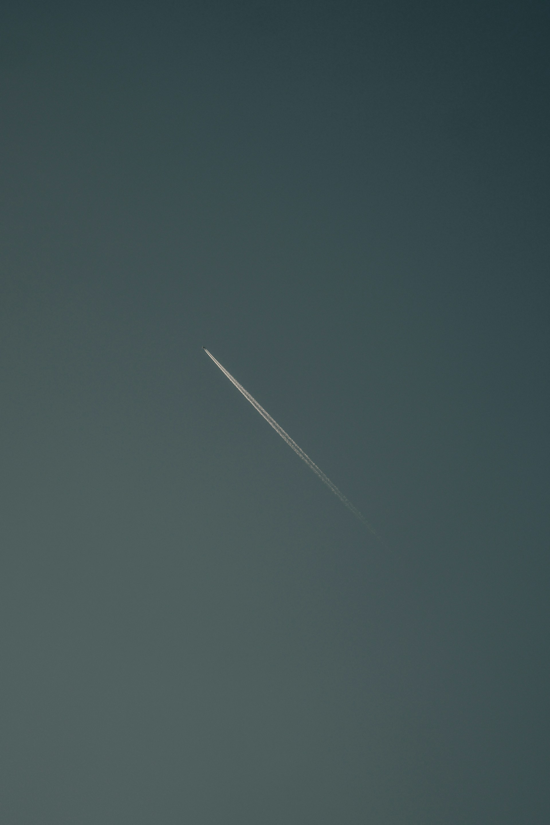 an airplane flying in the sky with a contrail