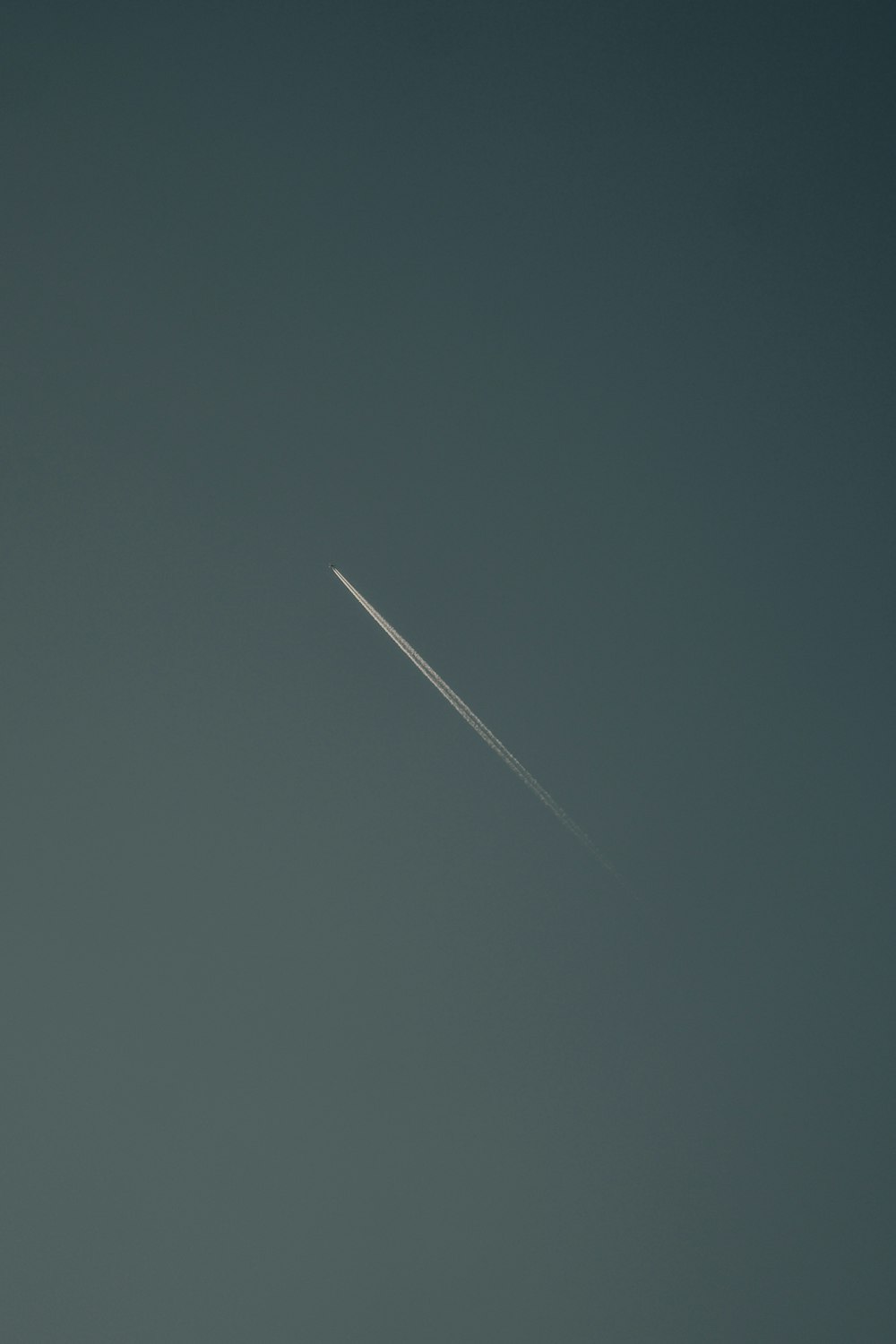 an airplane flying in the sky with a contrail