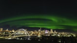 a green aurora bore over a city at night