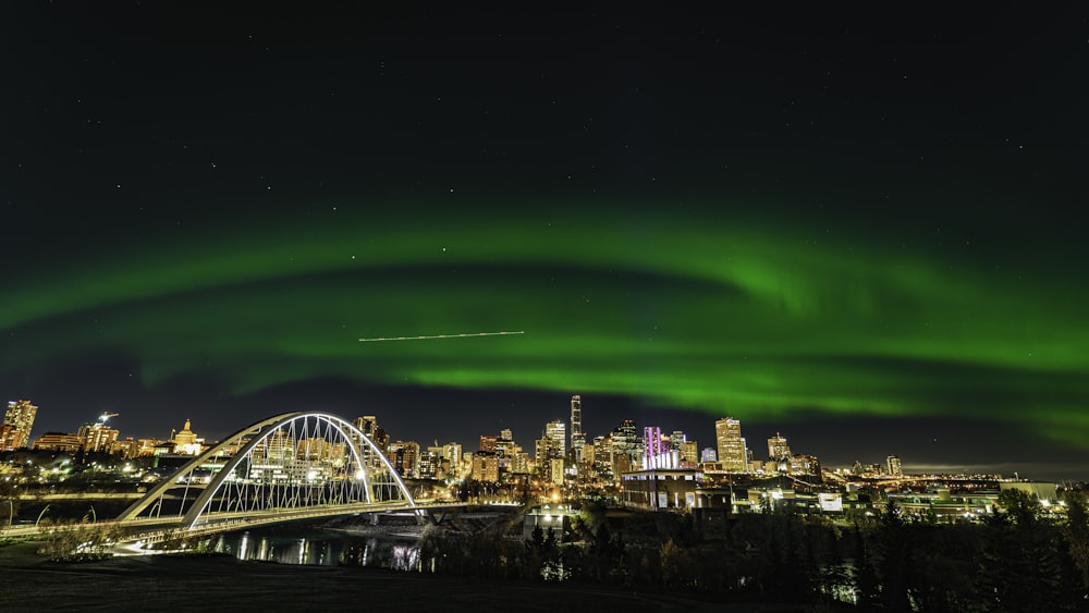 Eine grüne Aurora bohrt sich nachts über eine Stadt