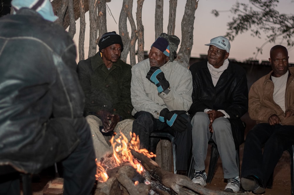 a group of men sitting around a fire pit