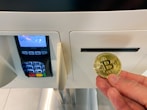 a hand holding a coin in front of a machine