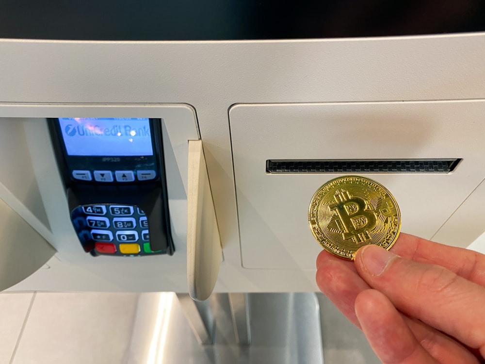 a hand holding a coin in front of a machine