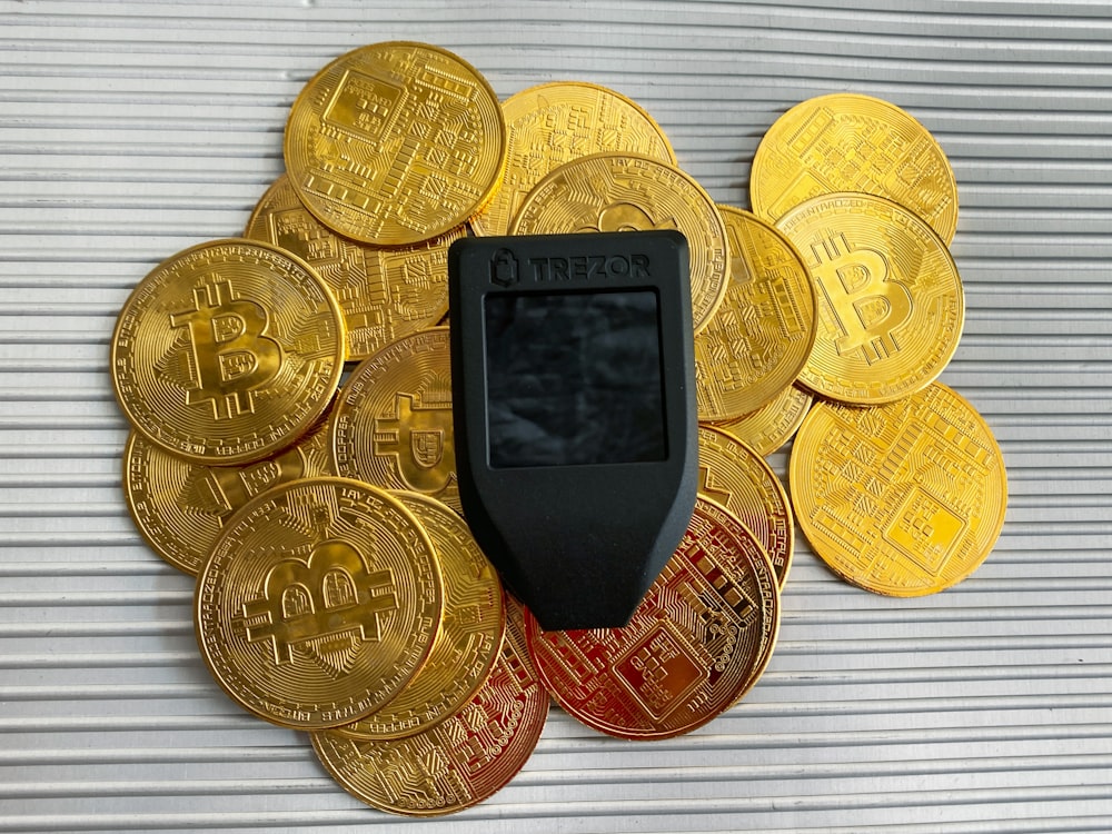 Un teléfono celular sentado encima de una pila de monedas de oro