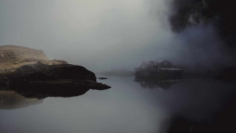 a foggy lake with a house in the distance