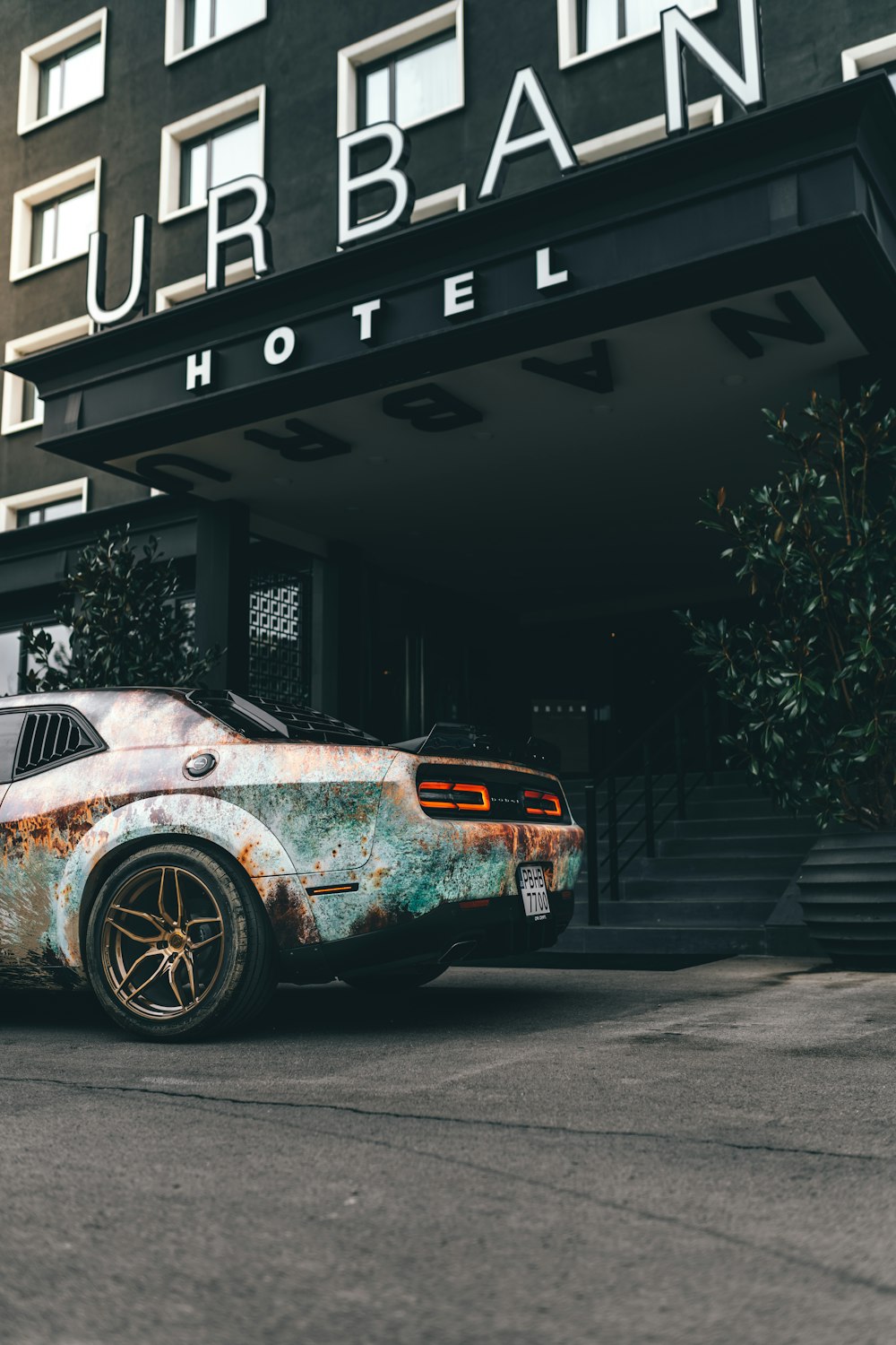 a rusted car parked in front of a hotel