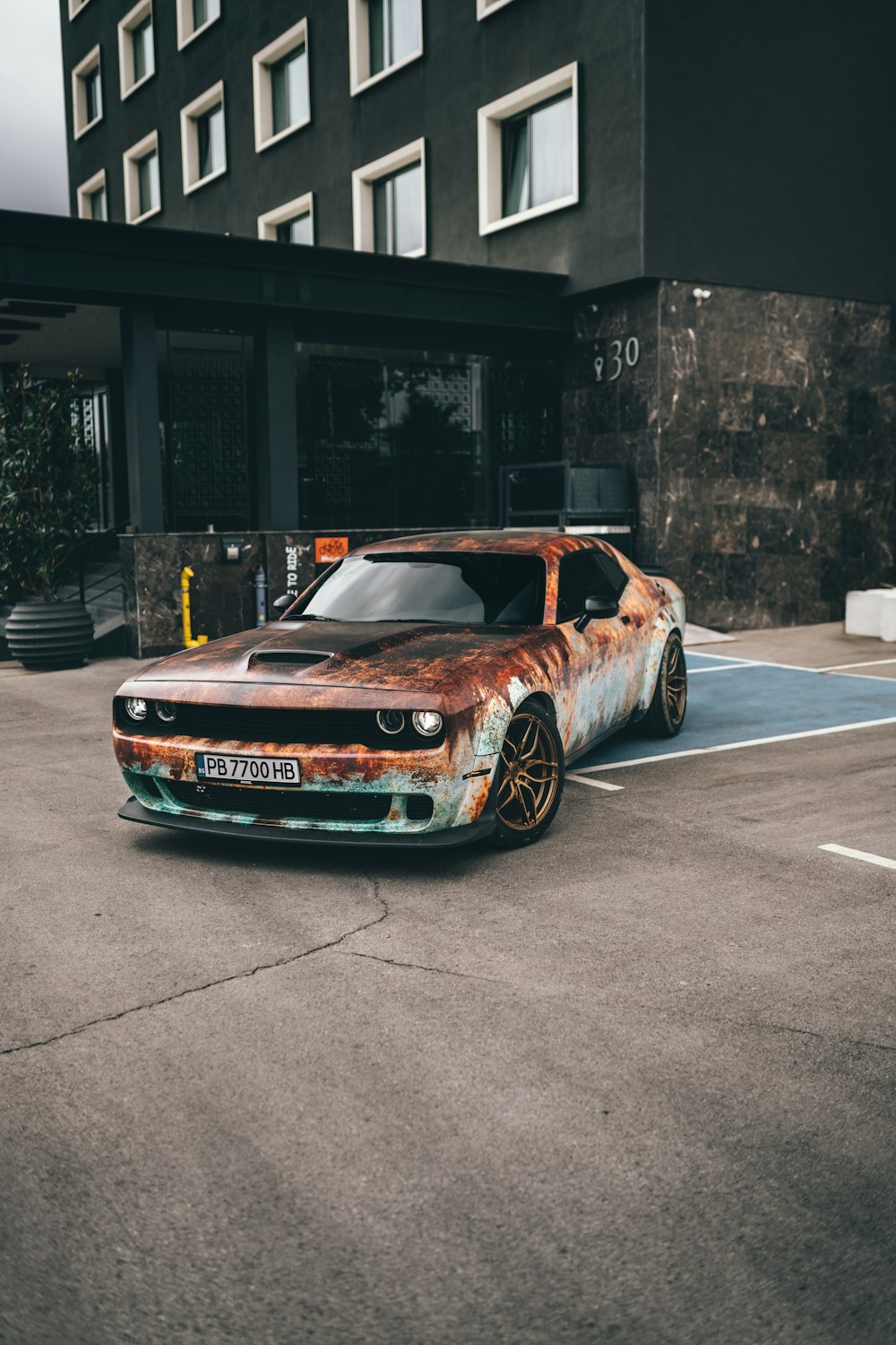 a rusted out car parked in a parking lot