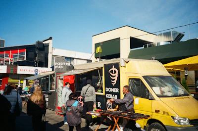 Lively scene of customers enjoying colorful kebap wraps at a bustling Mehringdamm street food stall.