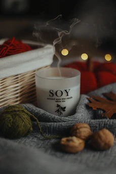 A softly glowing soy wax candle nestled among recycled leaves and earthy textures, evoking warmth and mindful living.