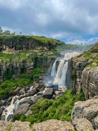 a waterfall in the middle of a lush green valley