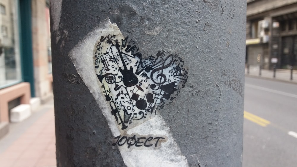 a sticker of a heart on a pole on a city street