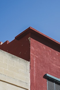 a red building with a clock on the side of it