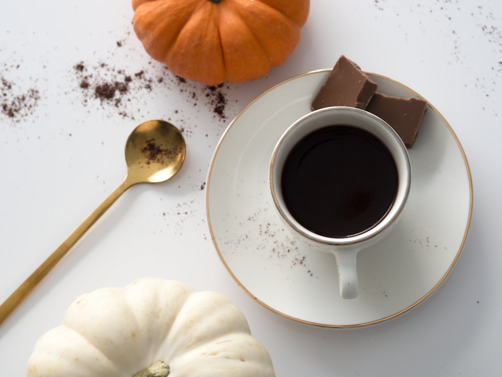 a cup of coffee and a spoon on a white table