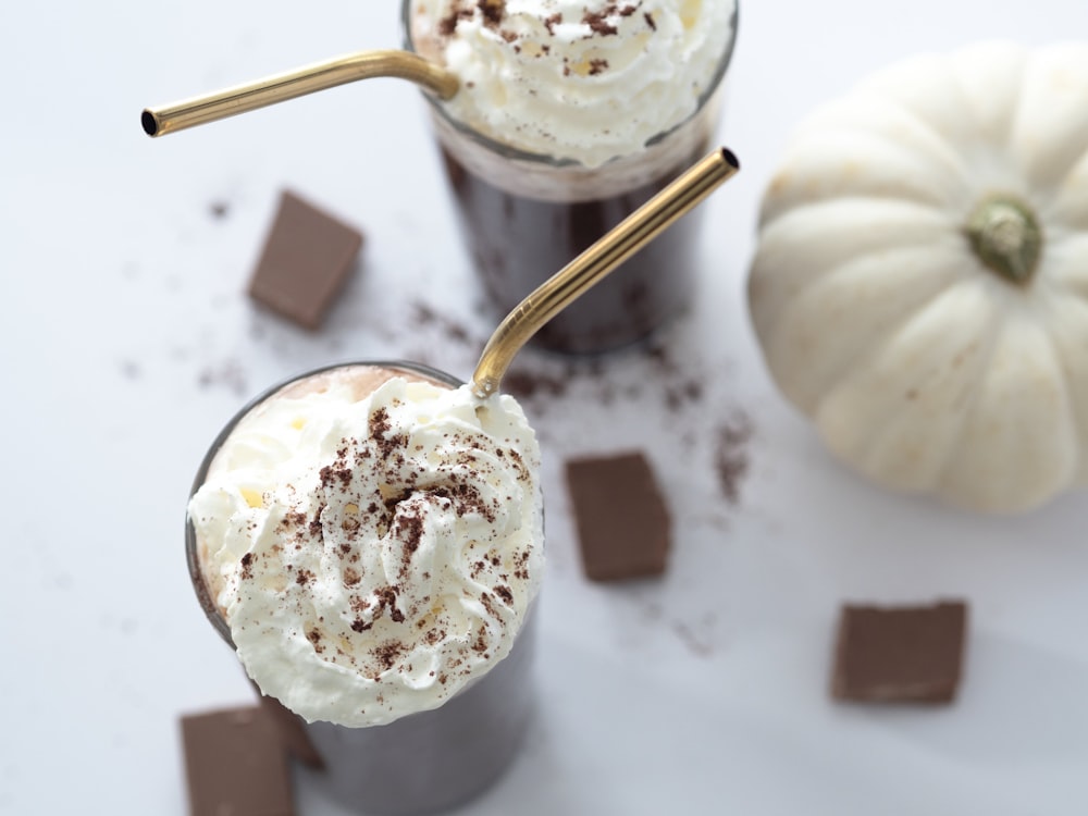 two glasses of chocolate milkshakes with whipped cream and chocolate chunks