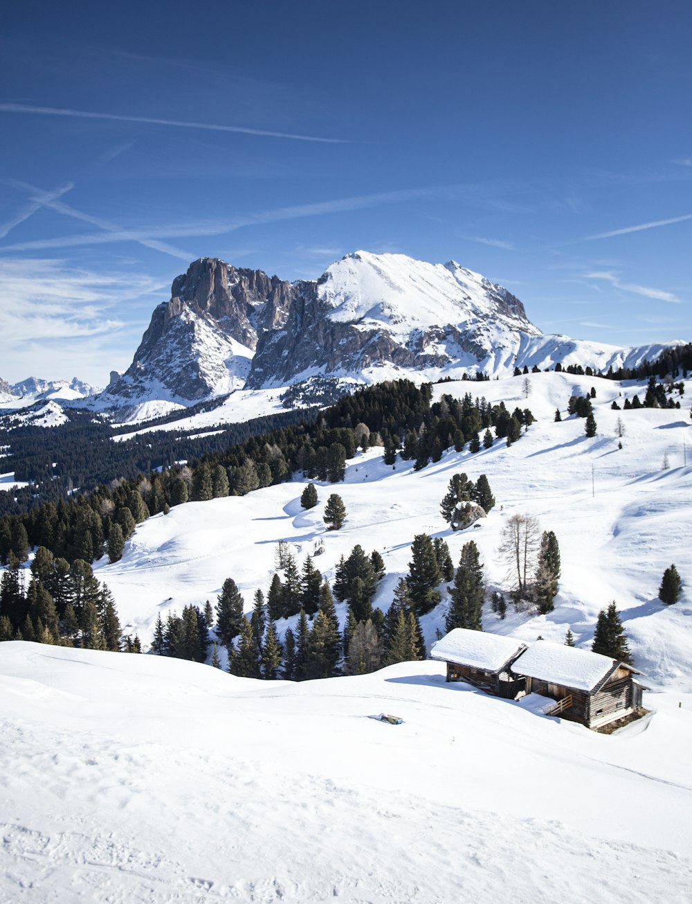 a snow covered mountain with a cabin in the foreground