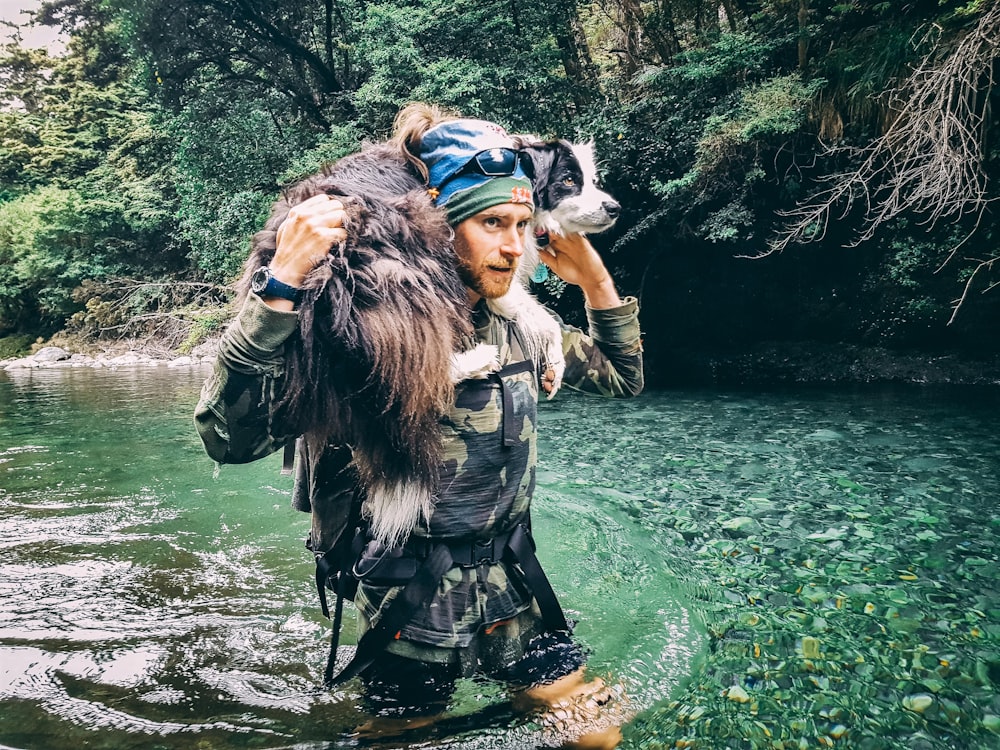 a man carrying a dog across a river