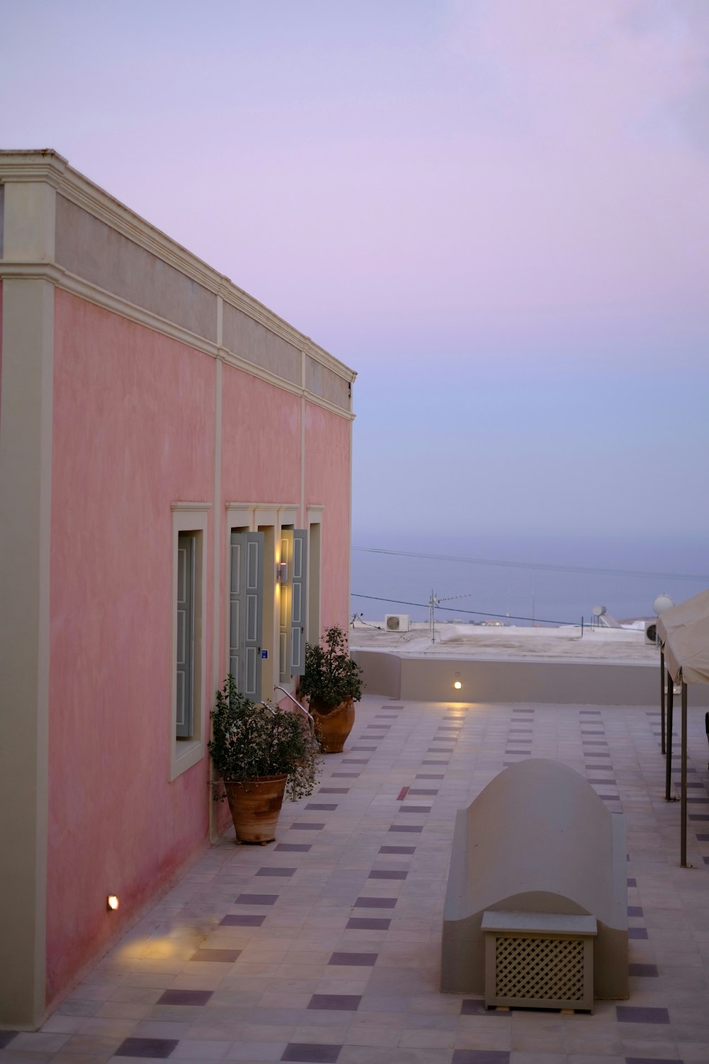 a pink building with potted plants on the roof