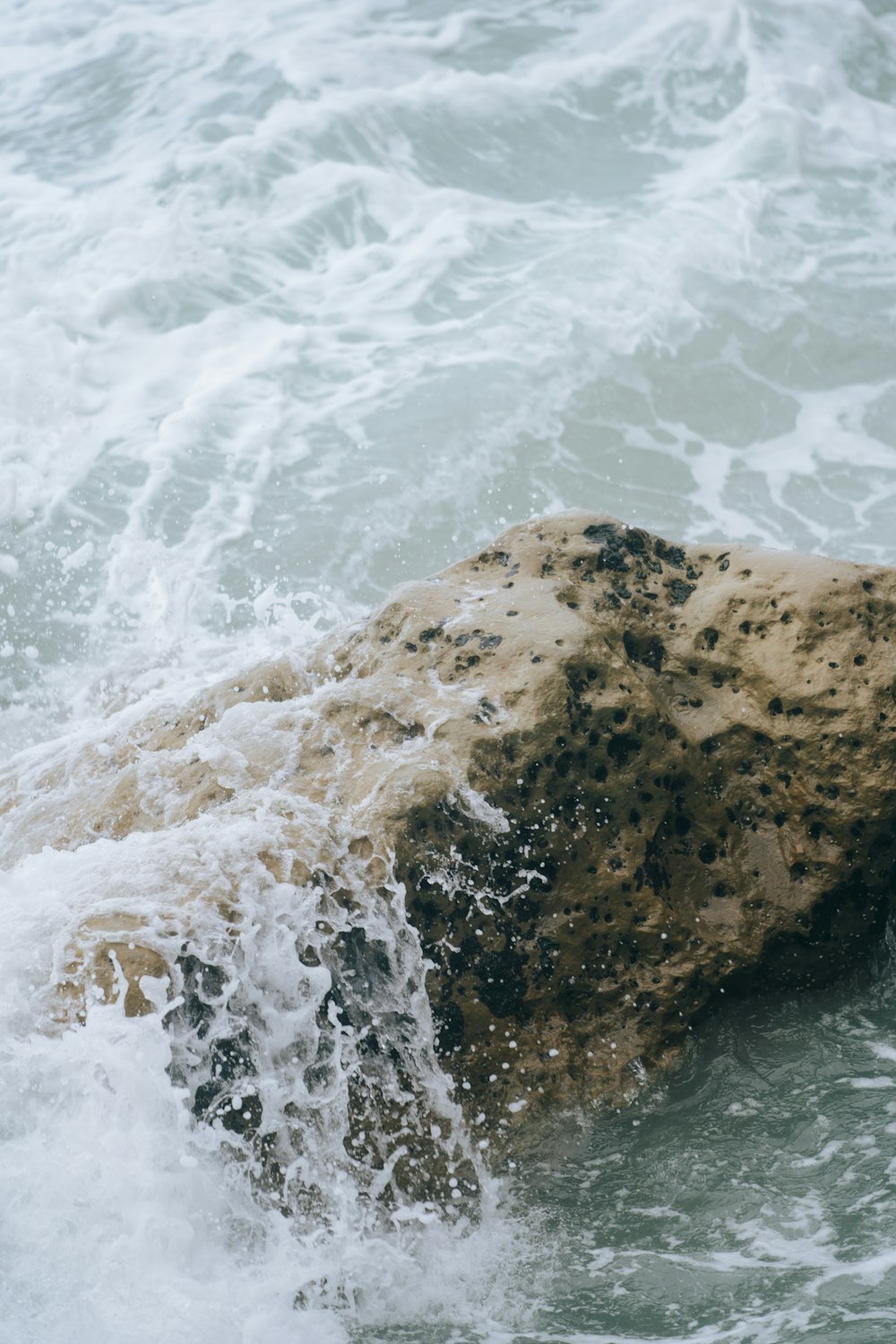 a rock sticking out of the ocean water