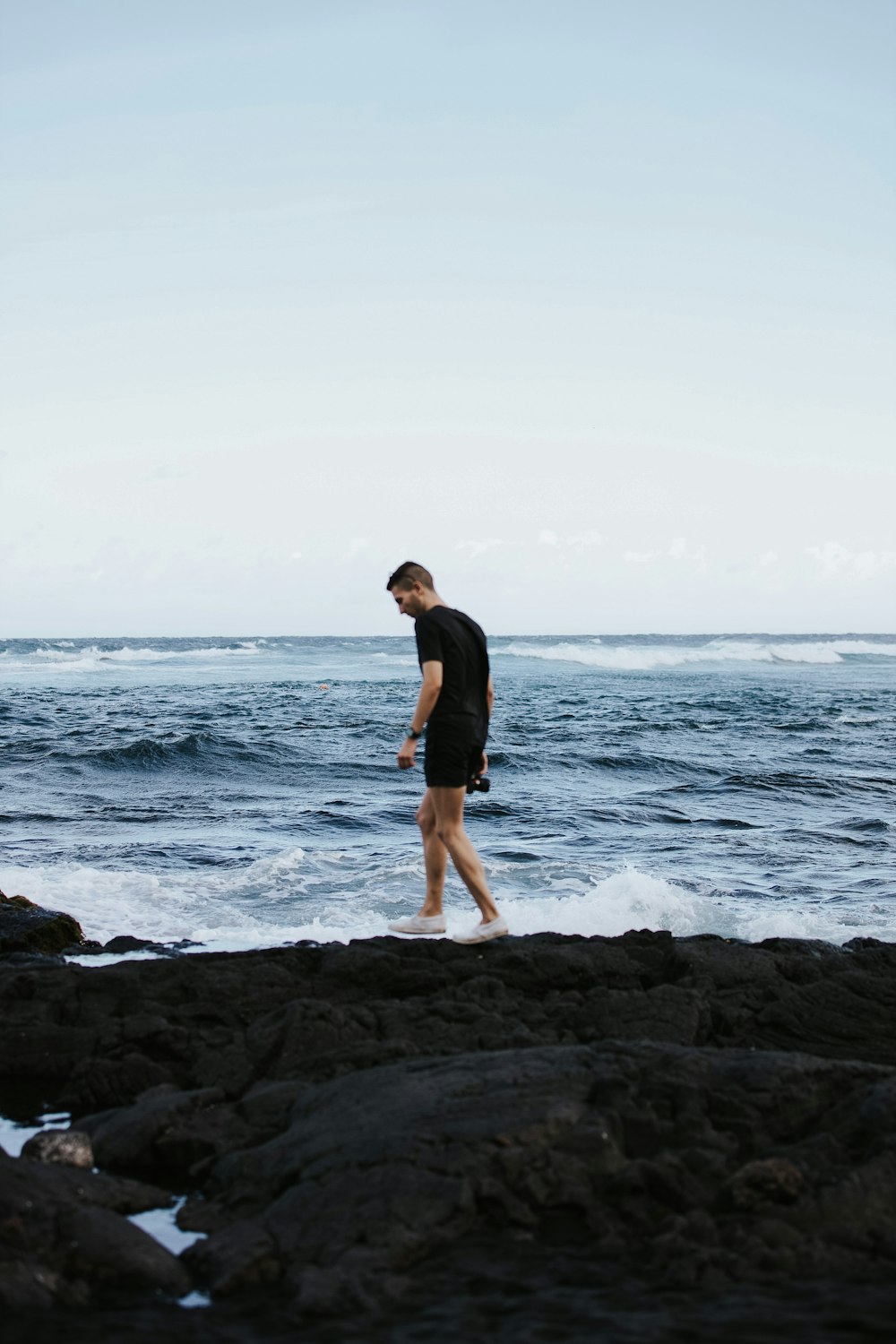 Un uomo che cammina lungo una spiaggia rocciosa vicino all'oceano