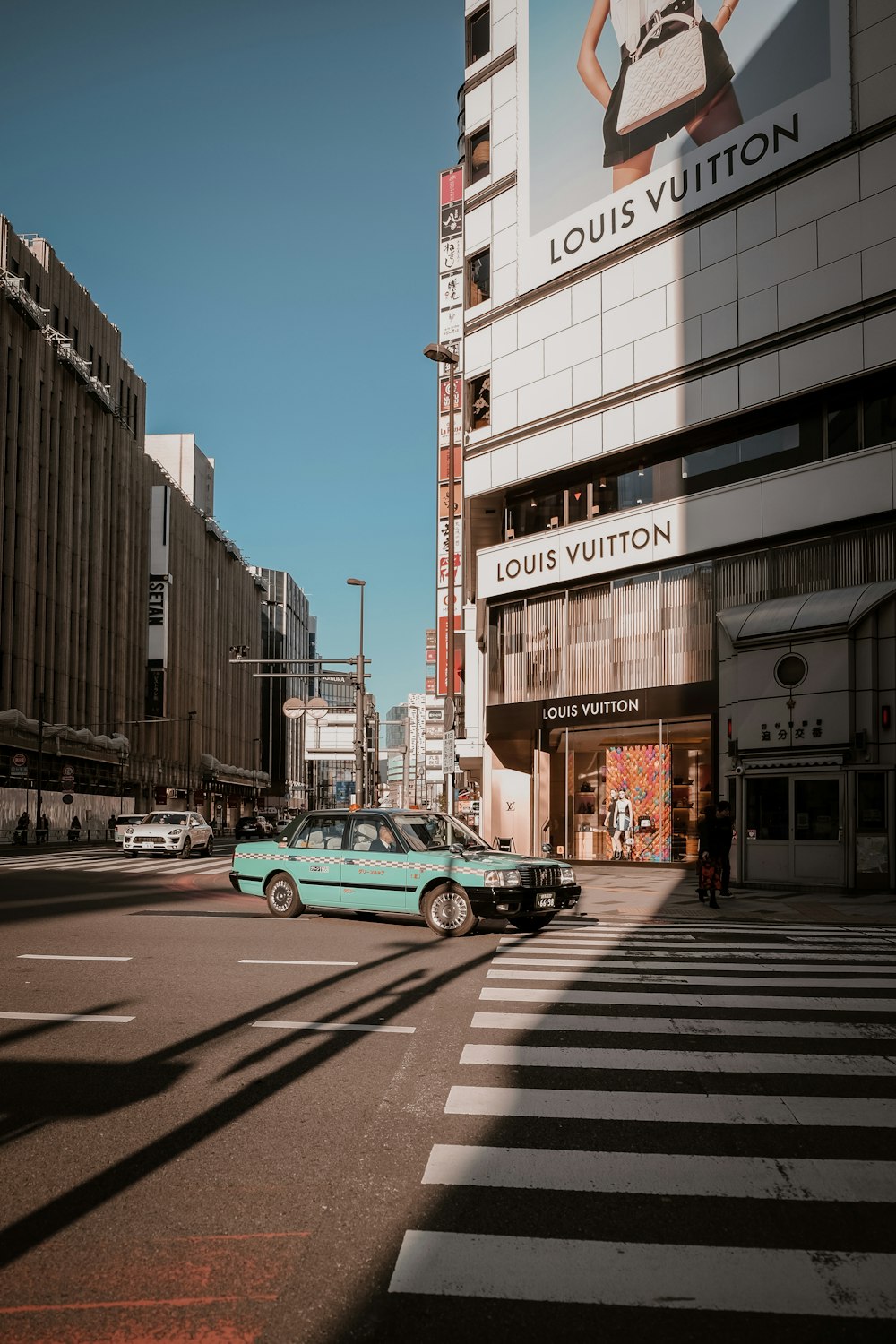 a blue car driving down a street next to tall buildings