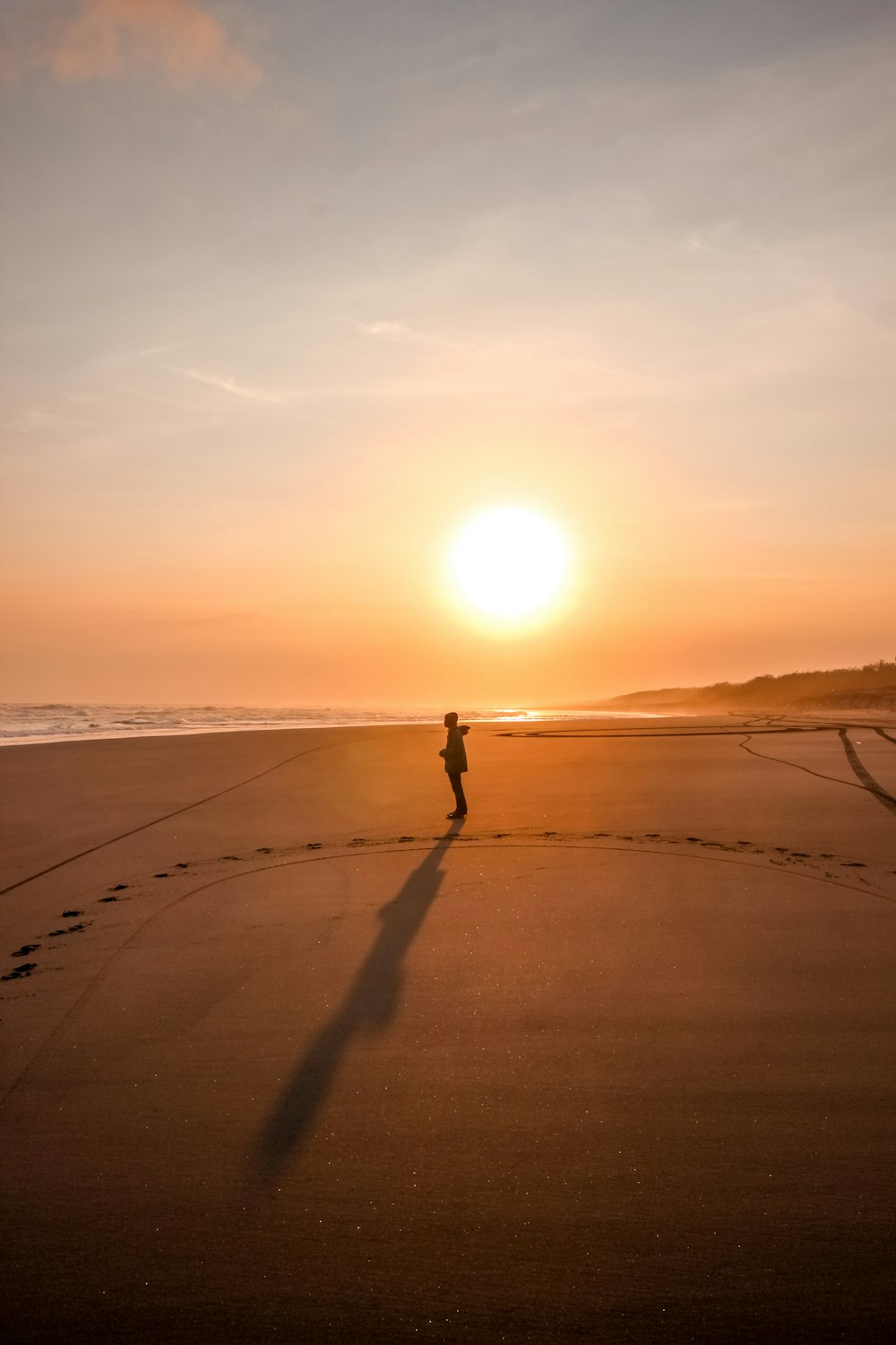 a person standing on a beach at sunset