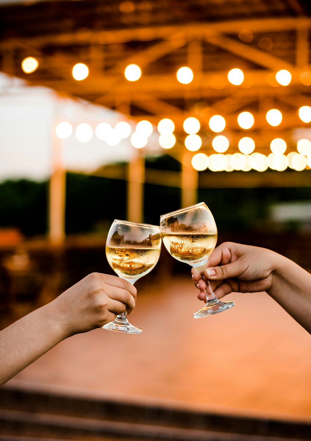 two people toasting with wine glasses in front of a stage