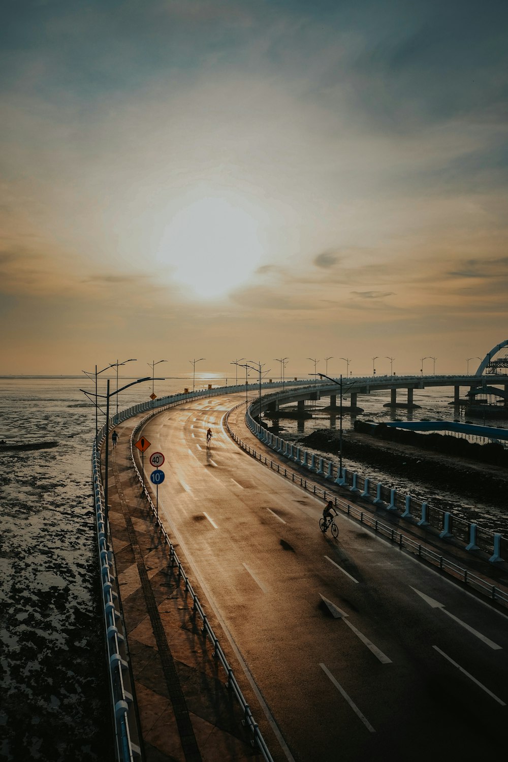 the sun is setting over a highway near the ocean