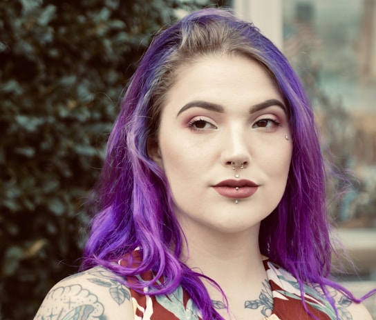 a woman with purple hair and tattoos on her chest