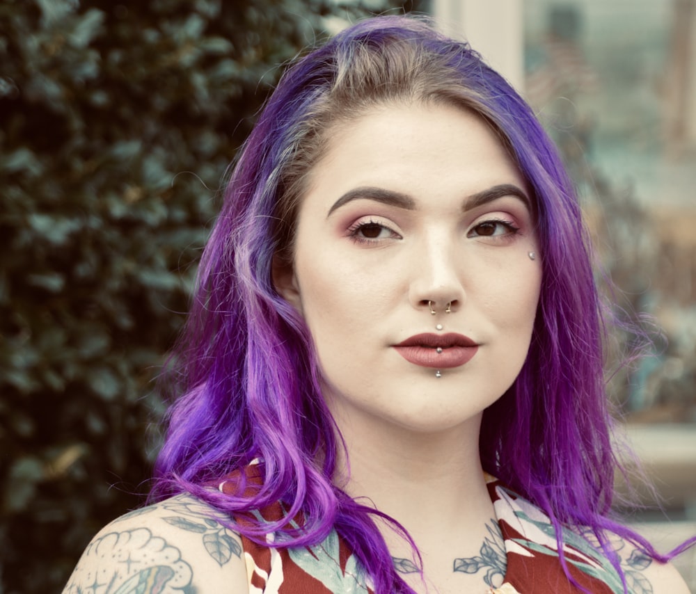 uma mulher com cabelo roxo e tatuagens no peito