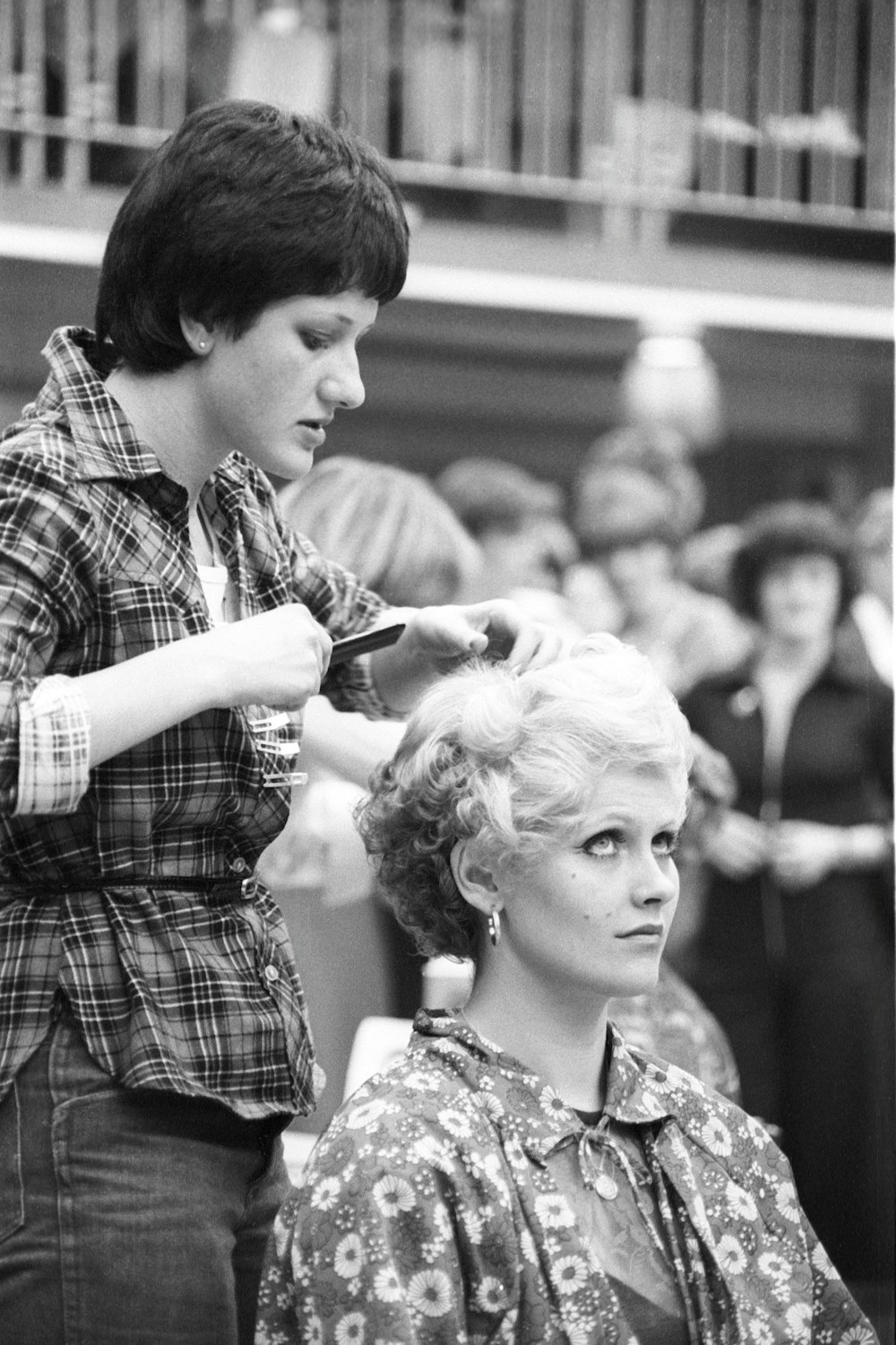 a black and white photo of a woman cutting another woman's hair