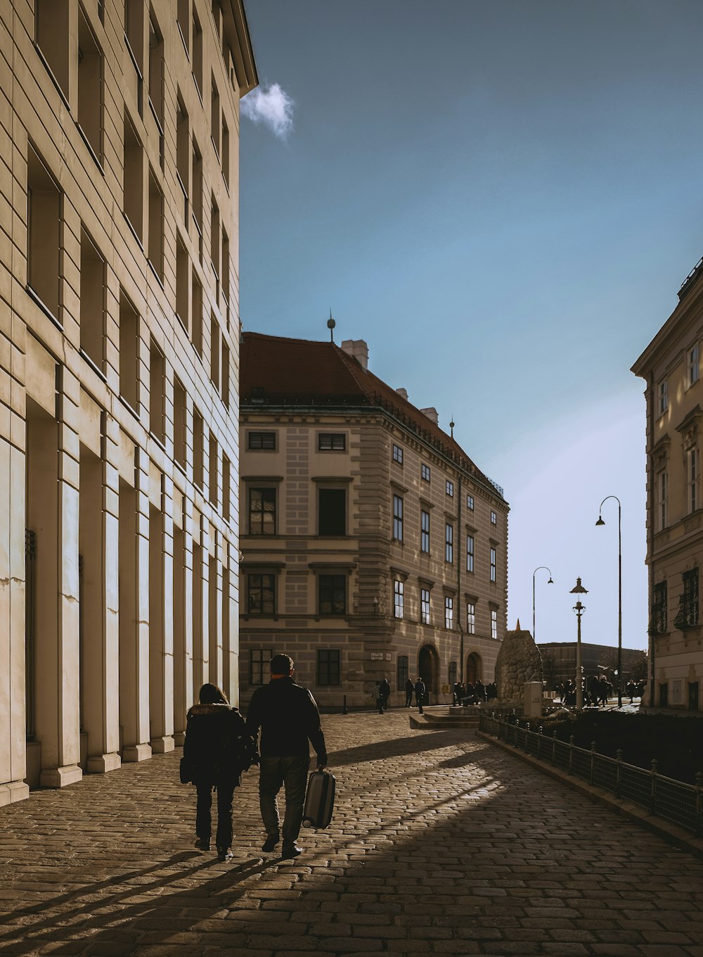 a couple of people walking down a street next to tall buildings