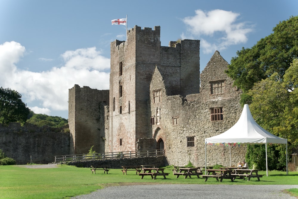a castle with a tent and picnic tables in front of it