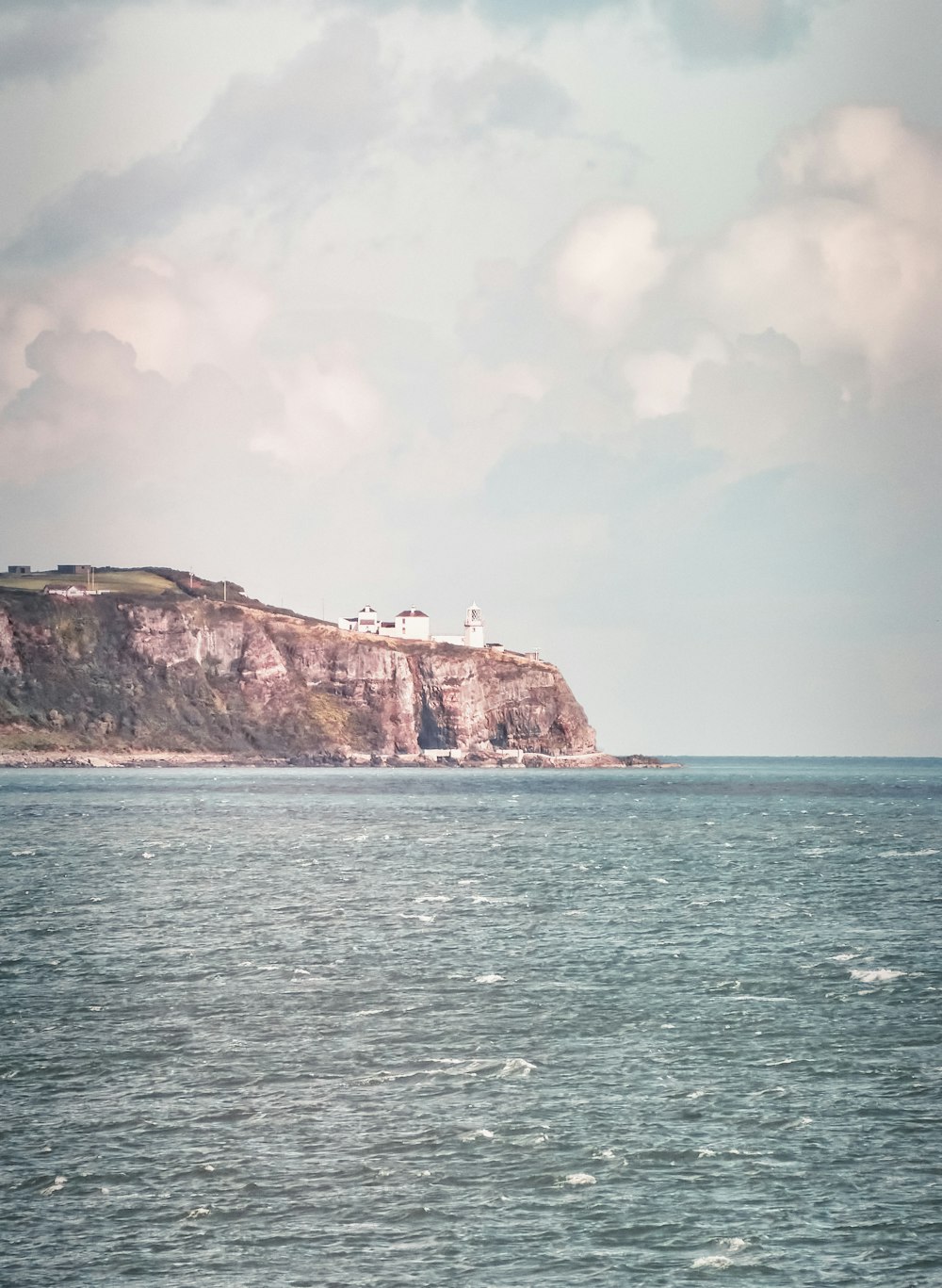 a large body of water with a lighthouse on a hill in the background