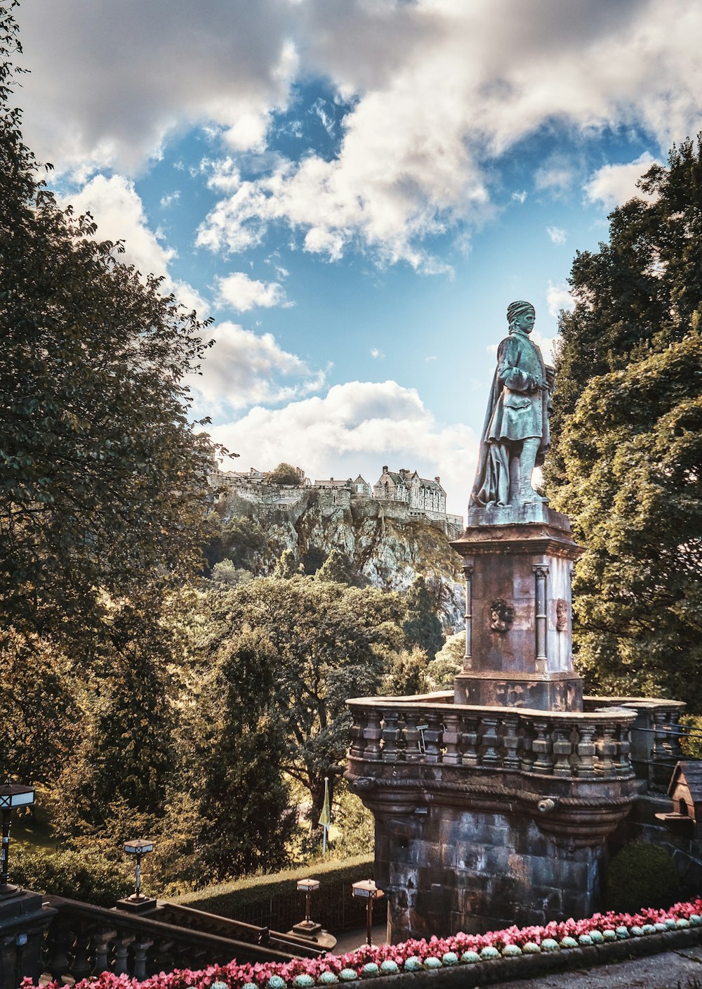 a statue in the middle of a park surrounded by trees