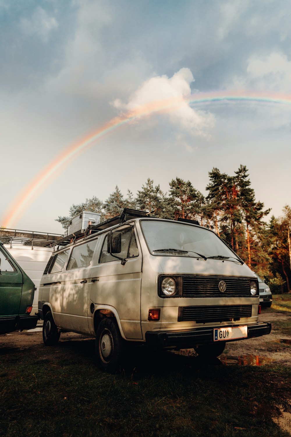a van parked next to a van with a rainbow in the background