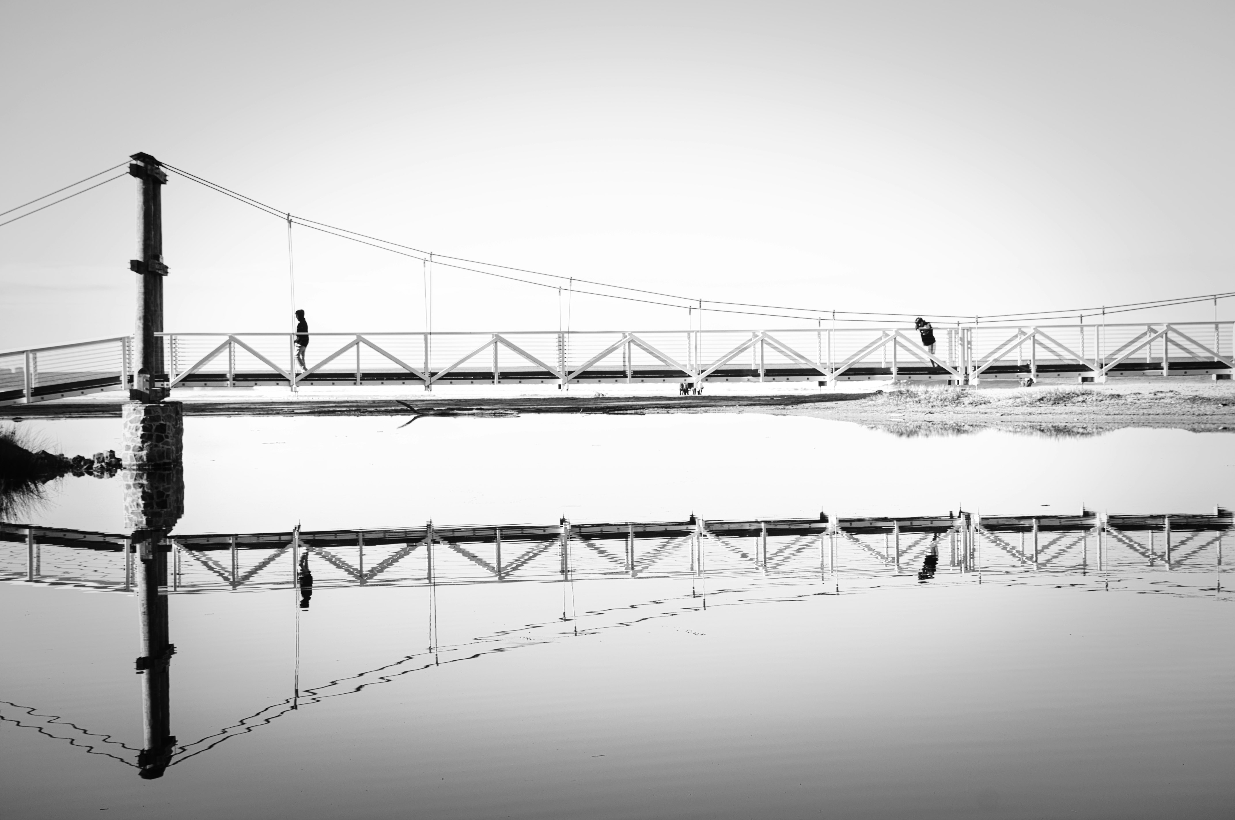 Black and white photo of Lorne swing bridge reflecting in water