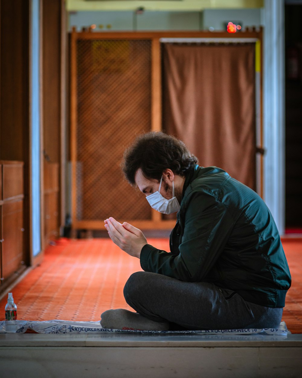 Un uomo seduto sul pavimento che indossa una maschera facciale