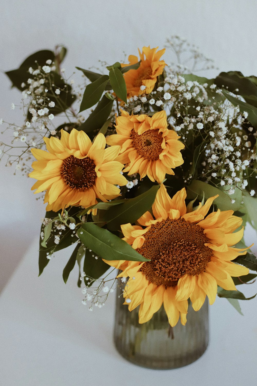 a vase filled with yellow sunflowers and baby's breath